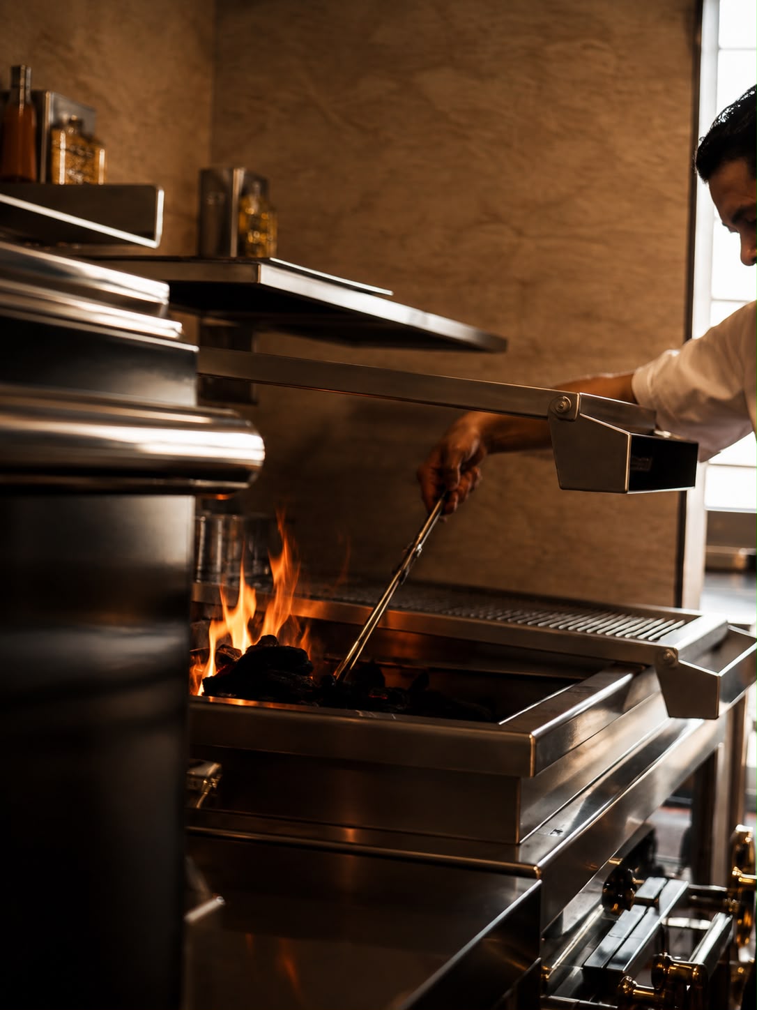 Cocinero atizando el carbón en la parrilla