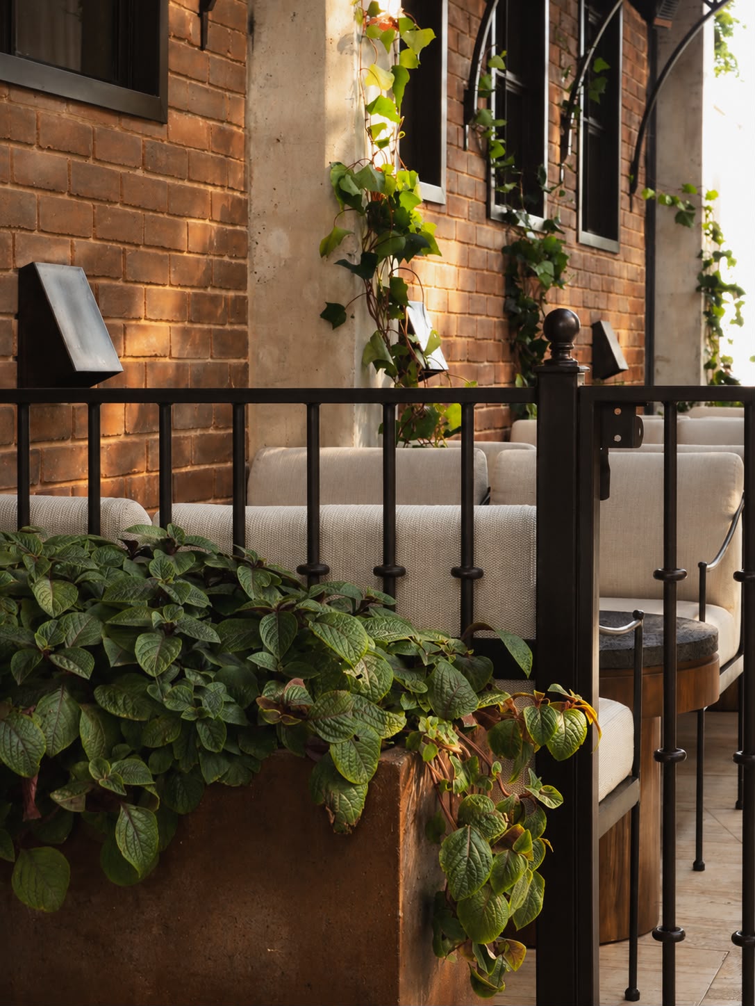 Terraza con sillones de lino, jardineras y muro de ladrillo al atardecer