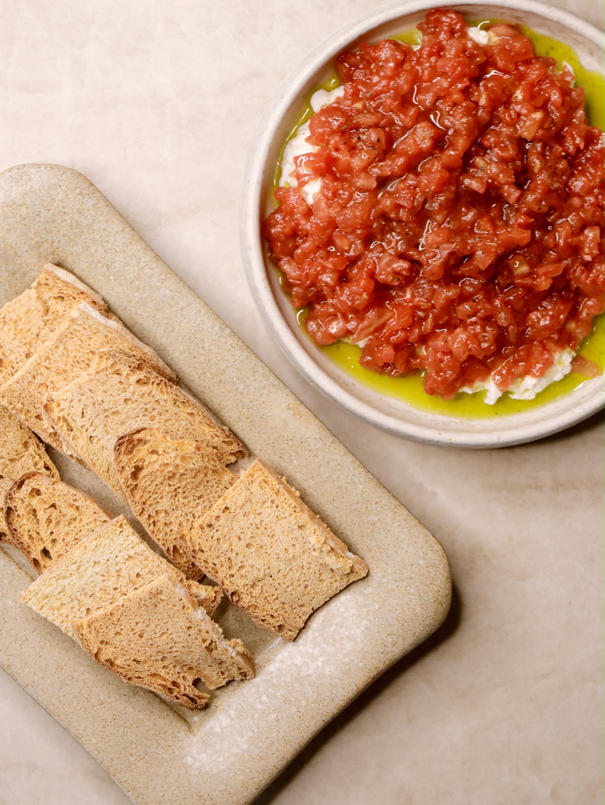 Tomate aliñado sobre queso fresco con aceite de oliva y pan